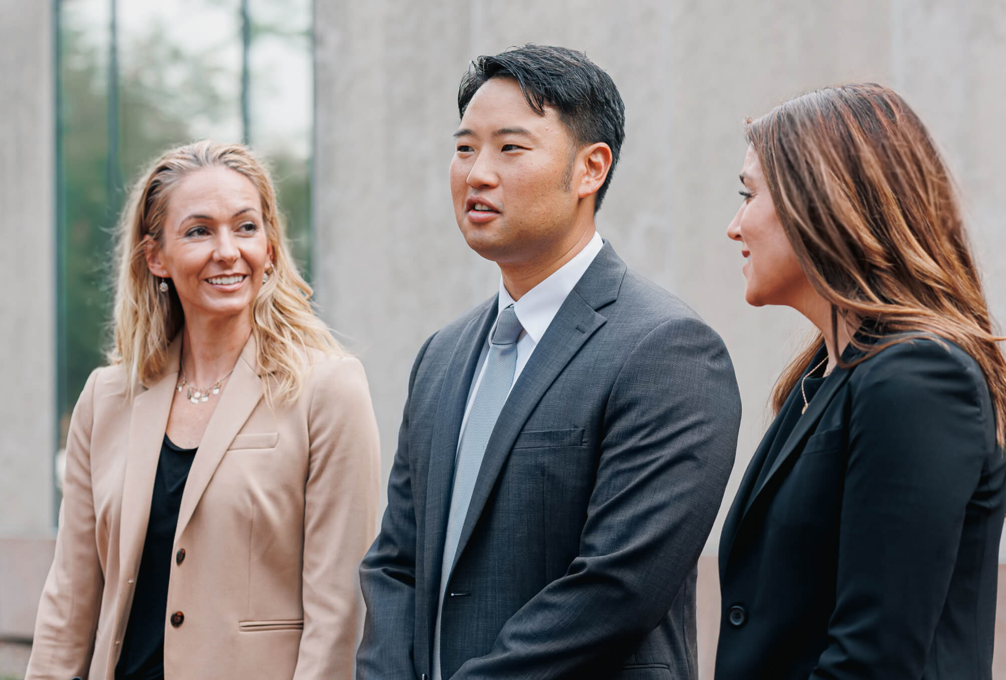 Three attorneys talking together while standing outside of an office building.