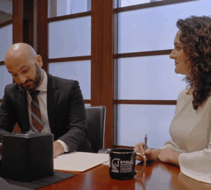 Two co-workers work together at desk in office.